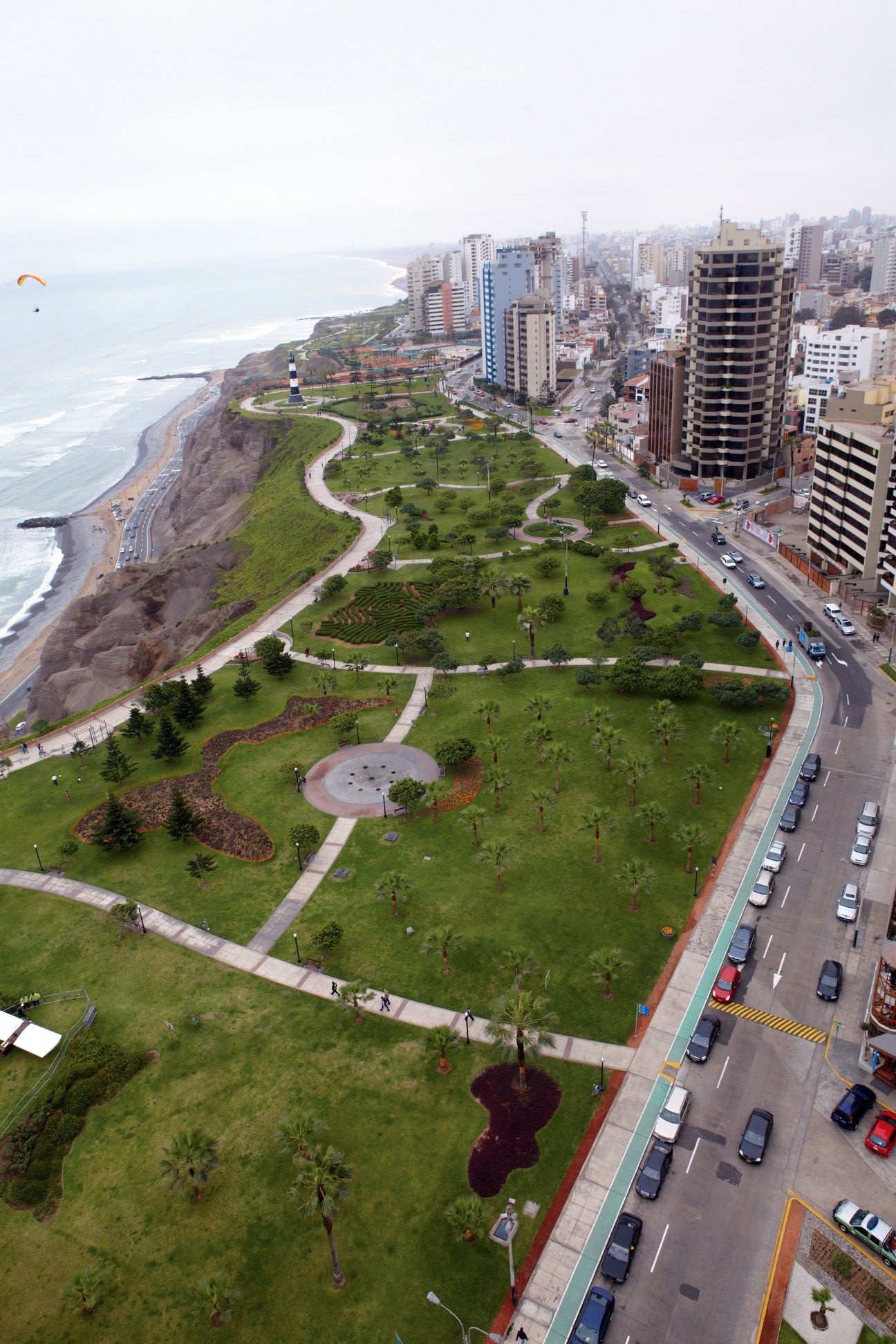 Aerial view of Malecon park in Lima's Miraflores district with ocean cliffs, green space, and high-rise buildings.