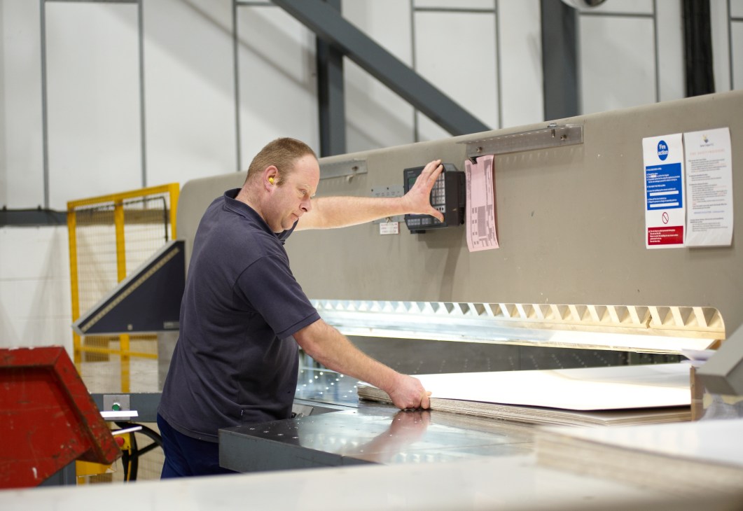 A worker operates a paper guillotine machine at James Cropper mill.