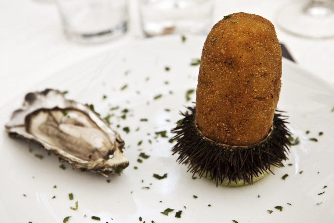 Sicilian arancina filled with seafood and risotto, garnished with chopped herbs.