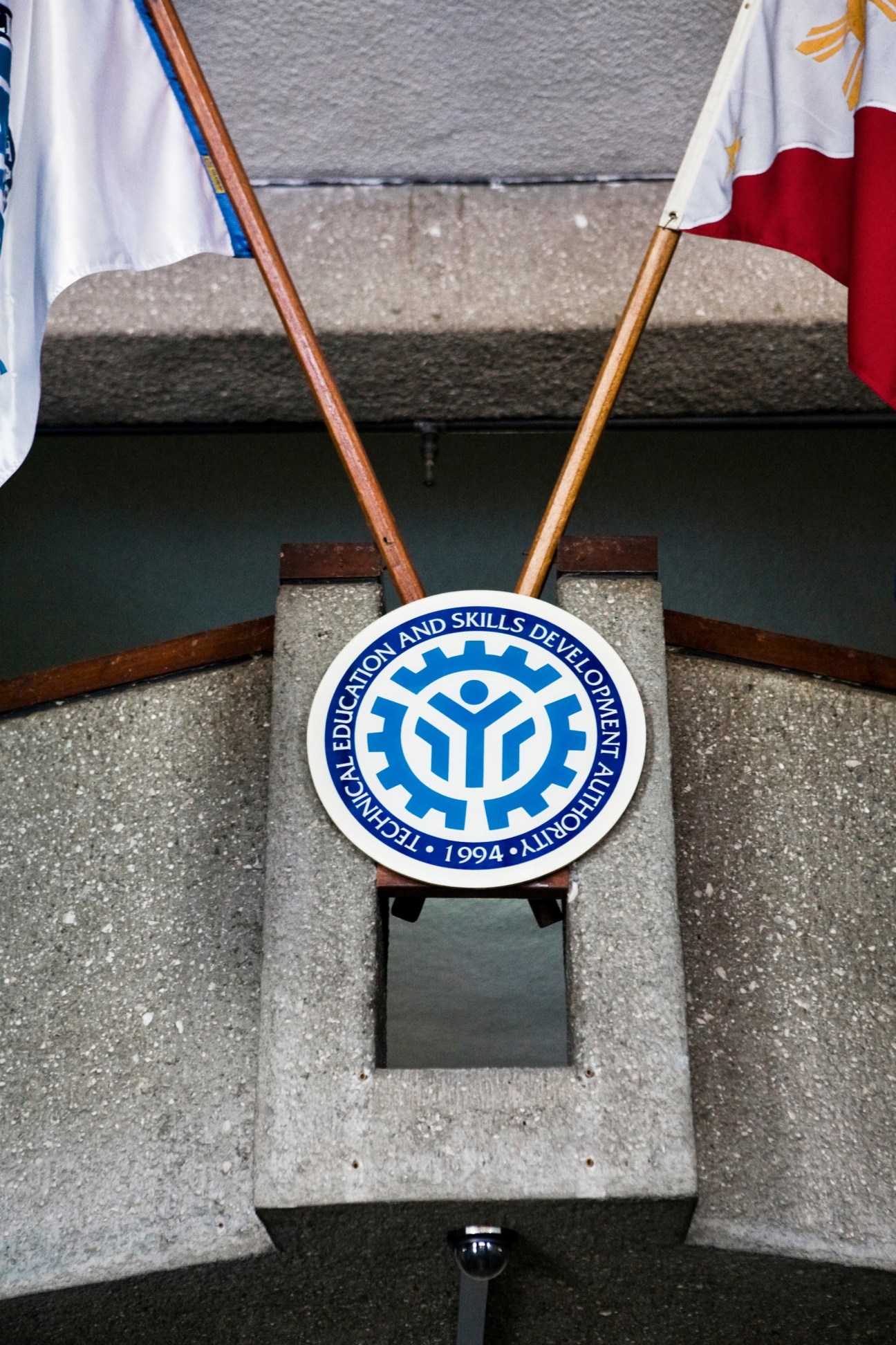 Tesda Technical Education and Skills Development Authority logo on concrete pillar with flags