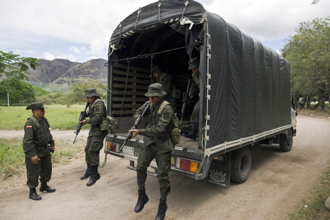 Colombian police officers in tactical uniforms disembarking from a military truck during training exercises.