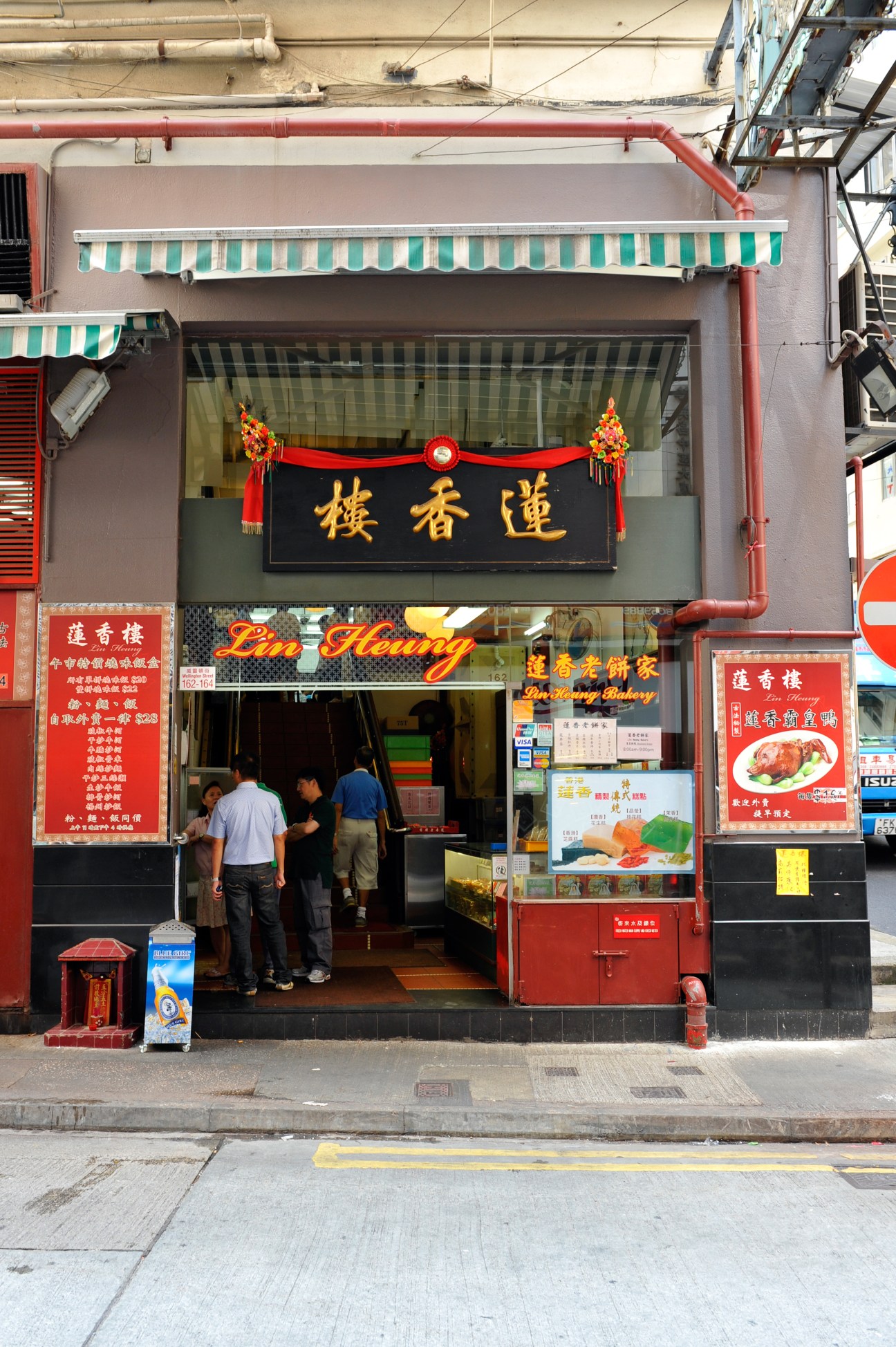 Lin Heung Tea House storefront with red signage and green striped awning on Wellington Street, Hong Kong.
