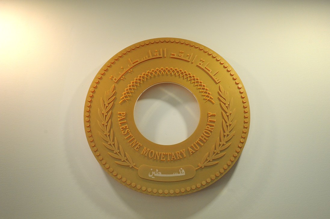 Gold circular emblem of the Palestine Monetary Authority with Arabic text and laurel wreaths.