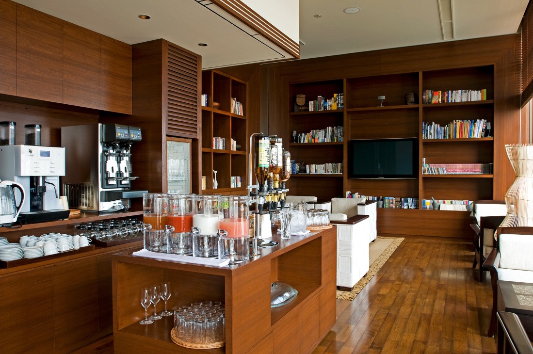 Lounge and library with wood cabinetry, bookshelves, and refreshment station at Sankara Hotel.