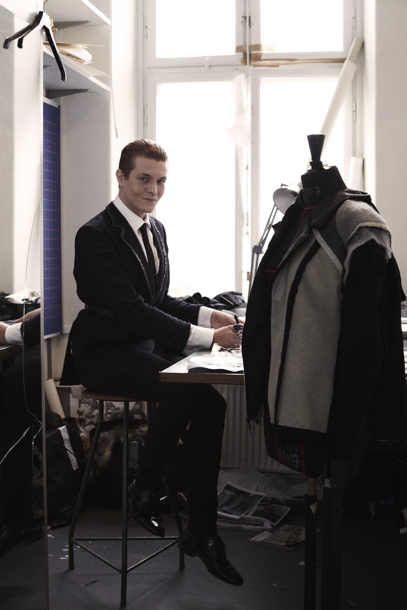 Fashion design student Kenni Kruse working at a table with a dress form in a studio.