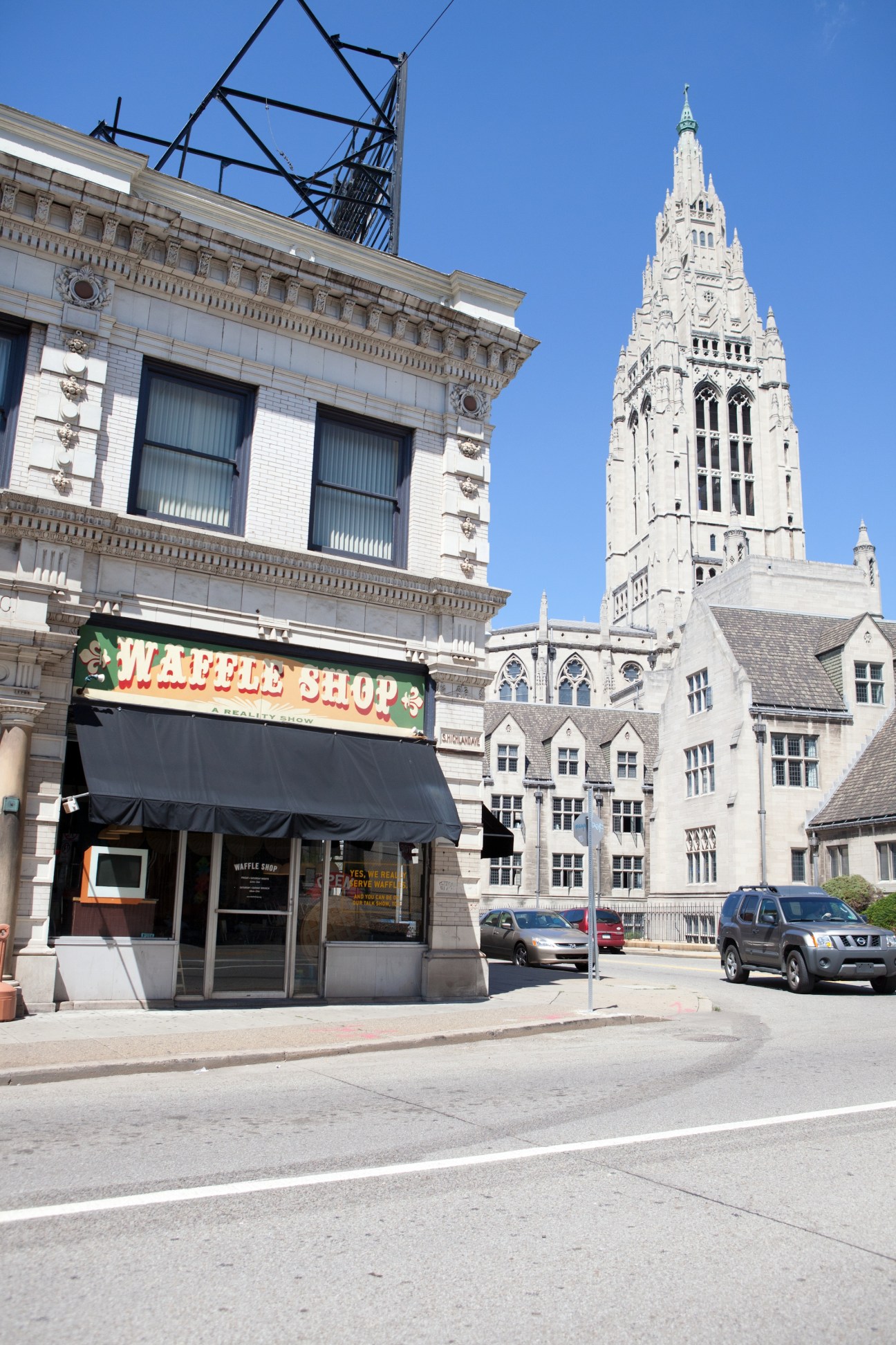 The Waffle Shop storefront with a white church spire visible behind it in Pittsburgh's East Liberty neighbourhood.