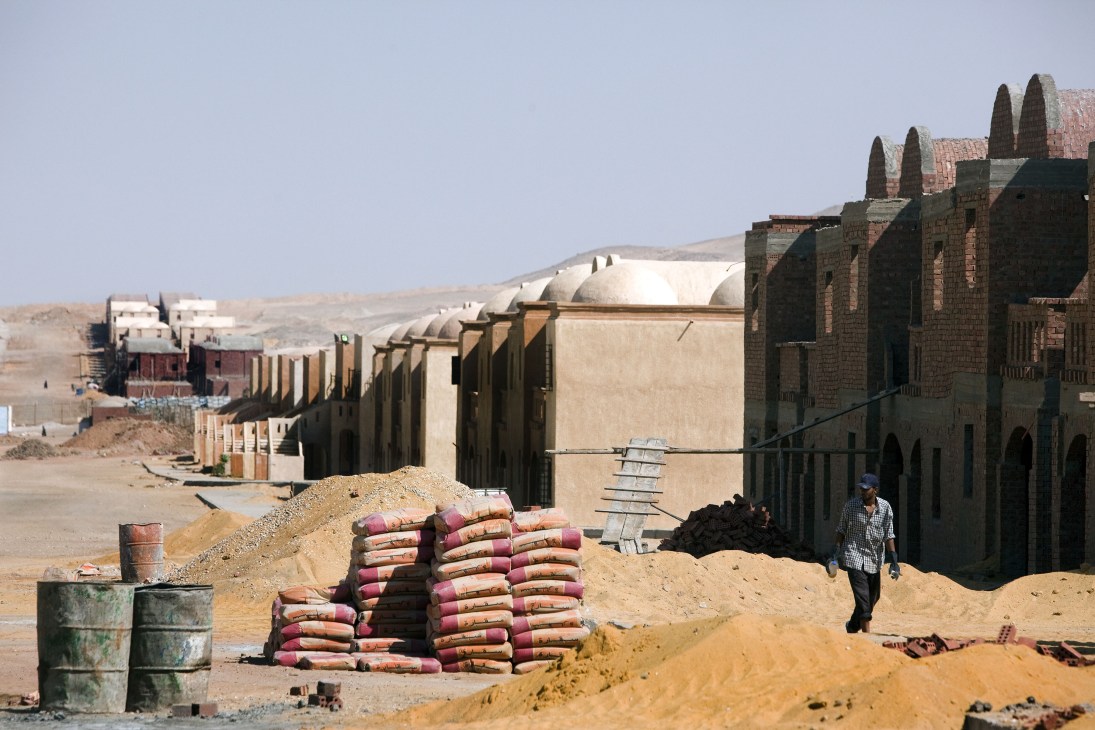 Cairo satellite city construction site with stacked cement bags, partially built structures, and desert landscape.