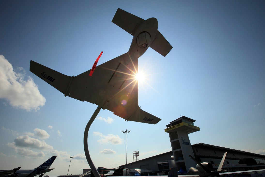 Military aircraft on display at Singapore Air Show with control tower in background