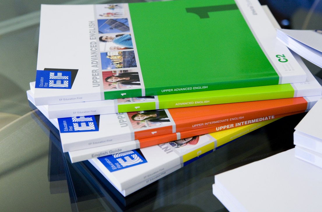 Stack of colorful EF English learning textbooks with blue logos arranged by proficiency level.