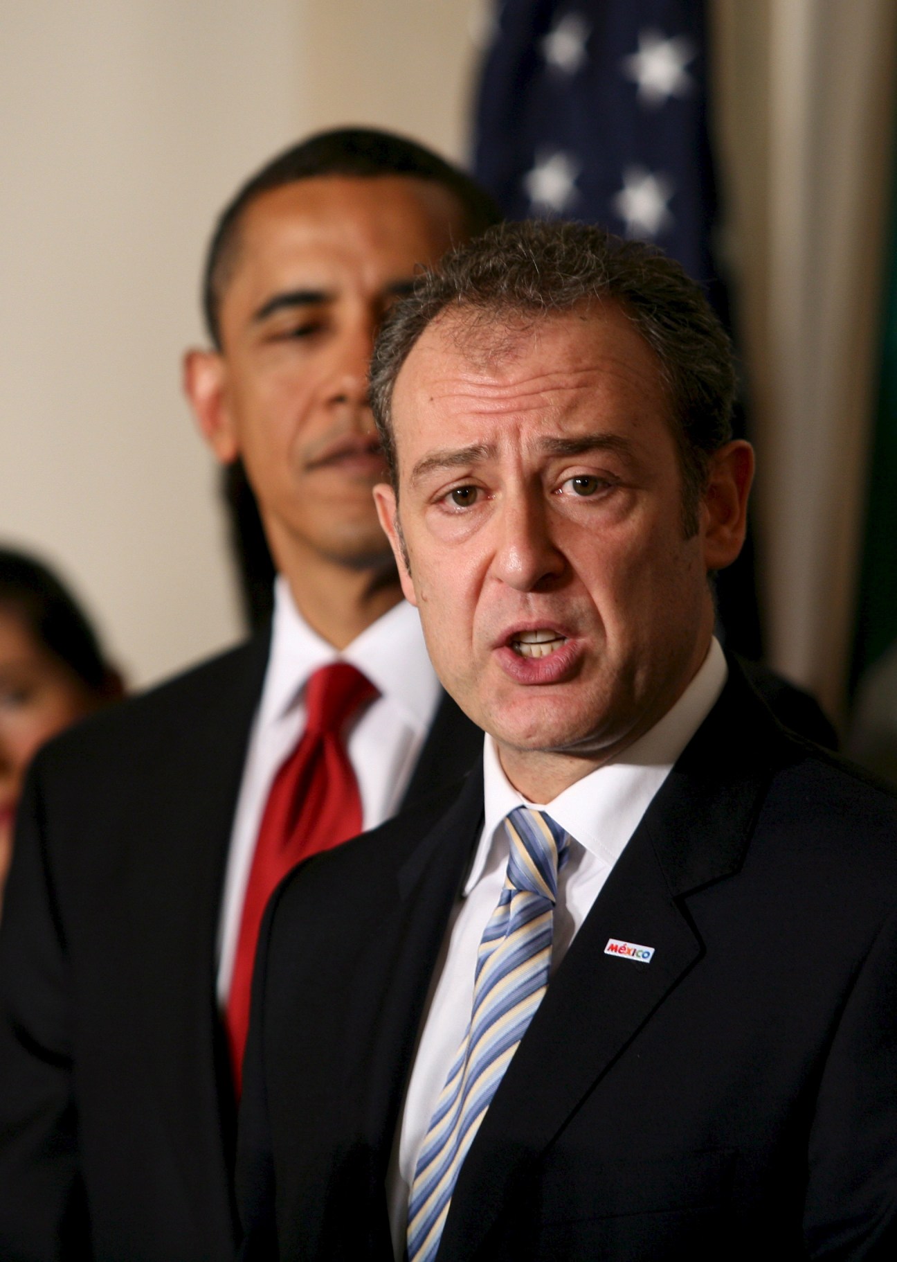 Mexican ambassador Arturo Sarukhan speaking at a podium with an American flag in the background.