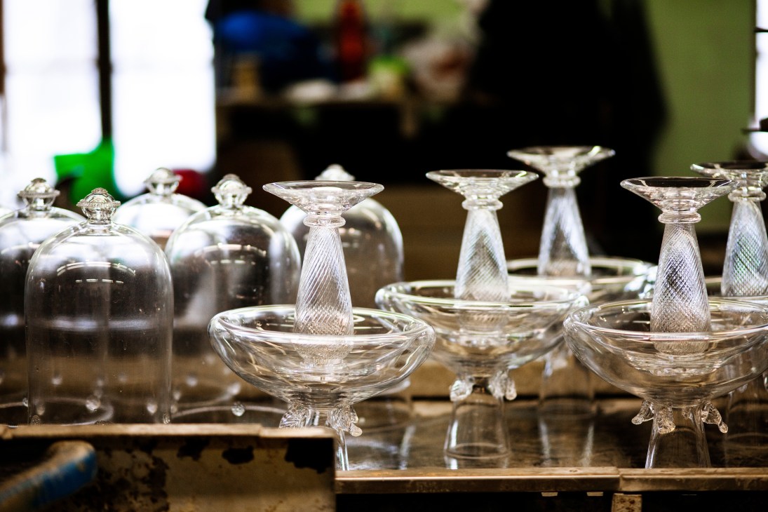 Handblown glass pieces cooling on a work surface in the Ajeto factory workshop.