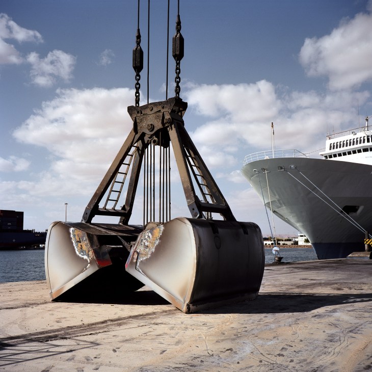 Crane jaw holding containers at DP World Sokhna container terminal with cargo ship in background.