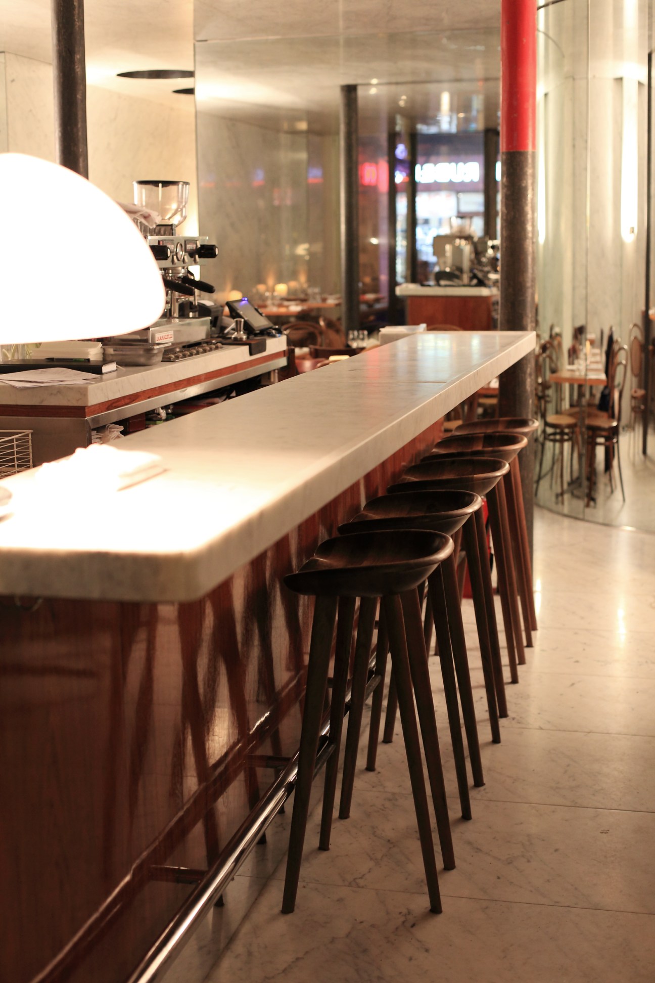 Le Dauphin restaurant's white marble U-shaped bar with black stools and modern lighting.