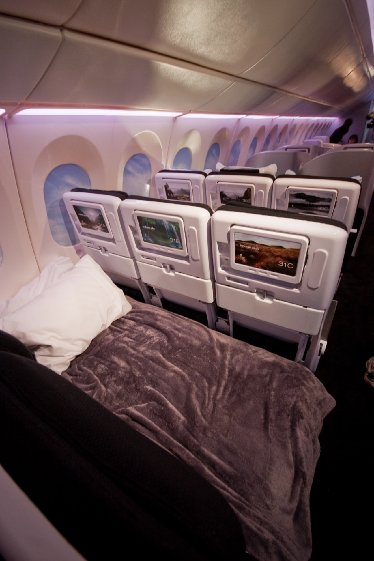 Air New Zealand Economy Skycouch showing three seats converted into a bed with bedding and entertainment screens.