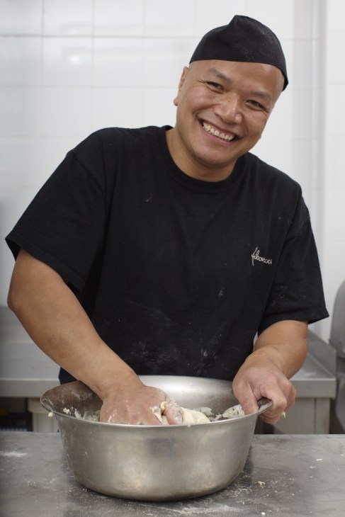 Baker kneading dough in a metal bowl at Fibonacci bakery in Mallorca.