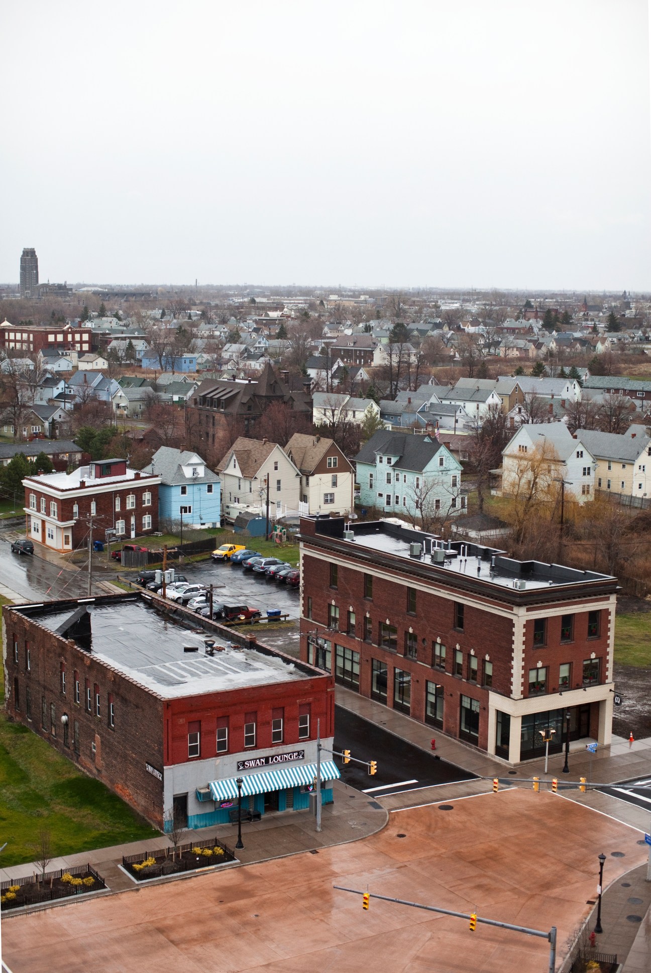 Aerial view of Buffalo showing brick buildings, historic neighborhoods, and a wide cityscape under grey sky.