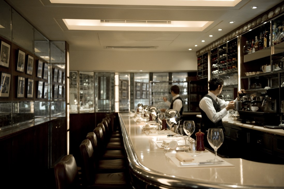 J Sheekey restaurant bar seating with place settings and staff in background.