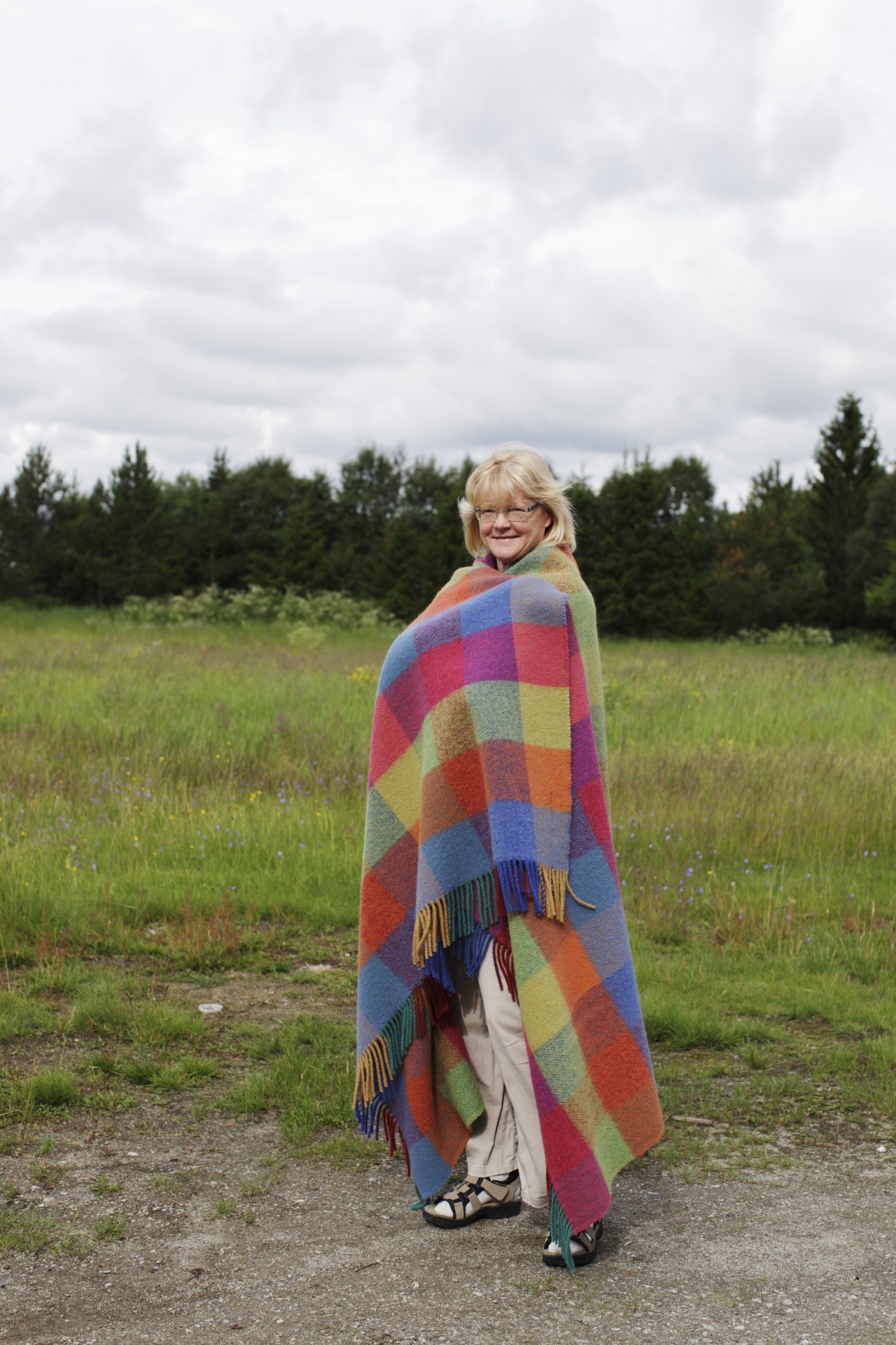 Worker Unni Tomas models a colorful patchwork wool blanket in a Norwegian field.