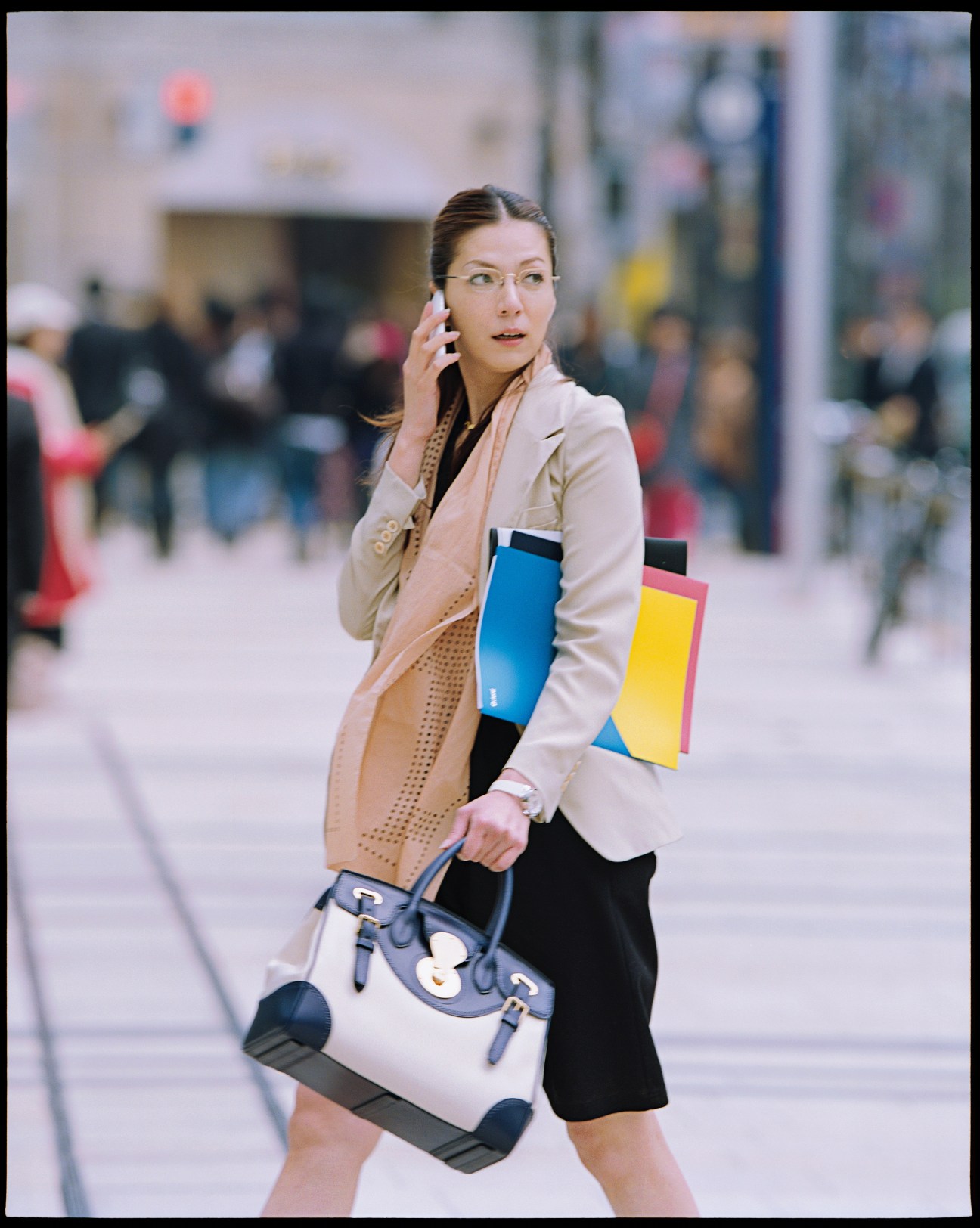 Model wearing Yves Saint Laurent jacket and scarf with colorful accessories on an urban street.