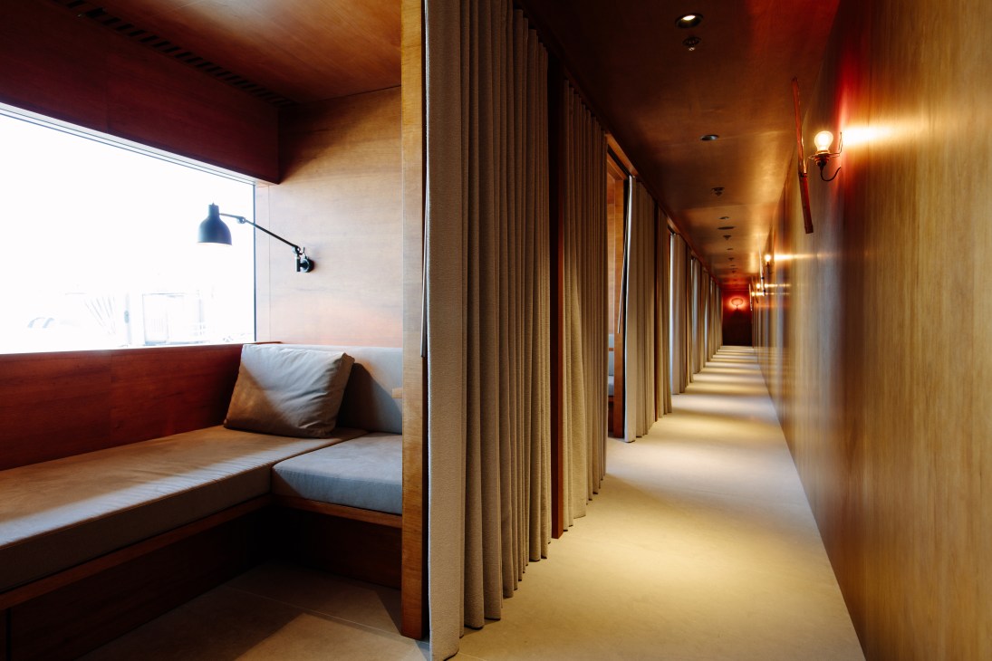 Cathay Pacific first-class lounge corridor with curved ceiling, warm lighting, and fabric partitions at Hong Kong Airport.