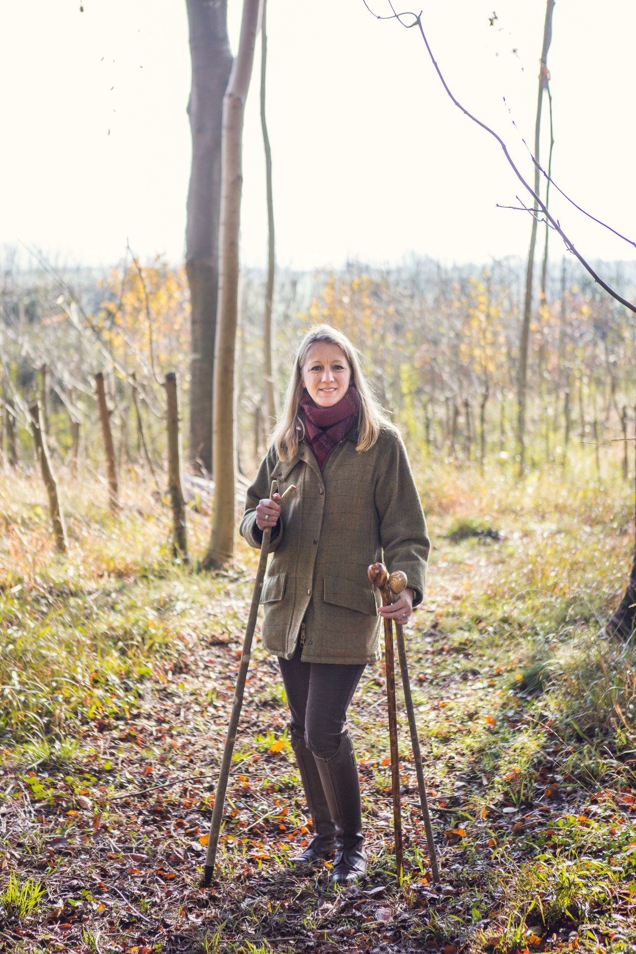 Charlotte Gillian, managing partner of Classic Canes, stands in a vineyard holding walking sticks.