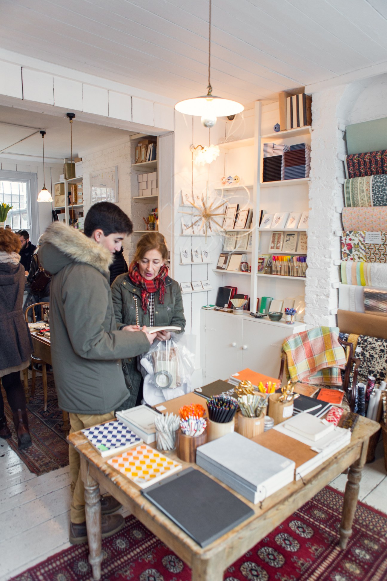 Interior of Choosing Keeping stationery shop with customers browsing displayed notebooks and art supplies.