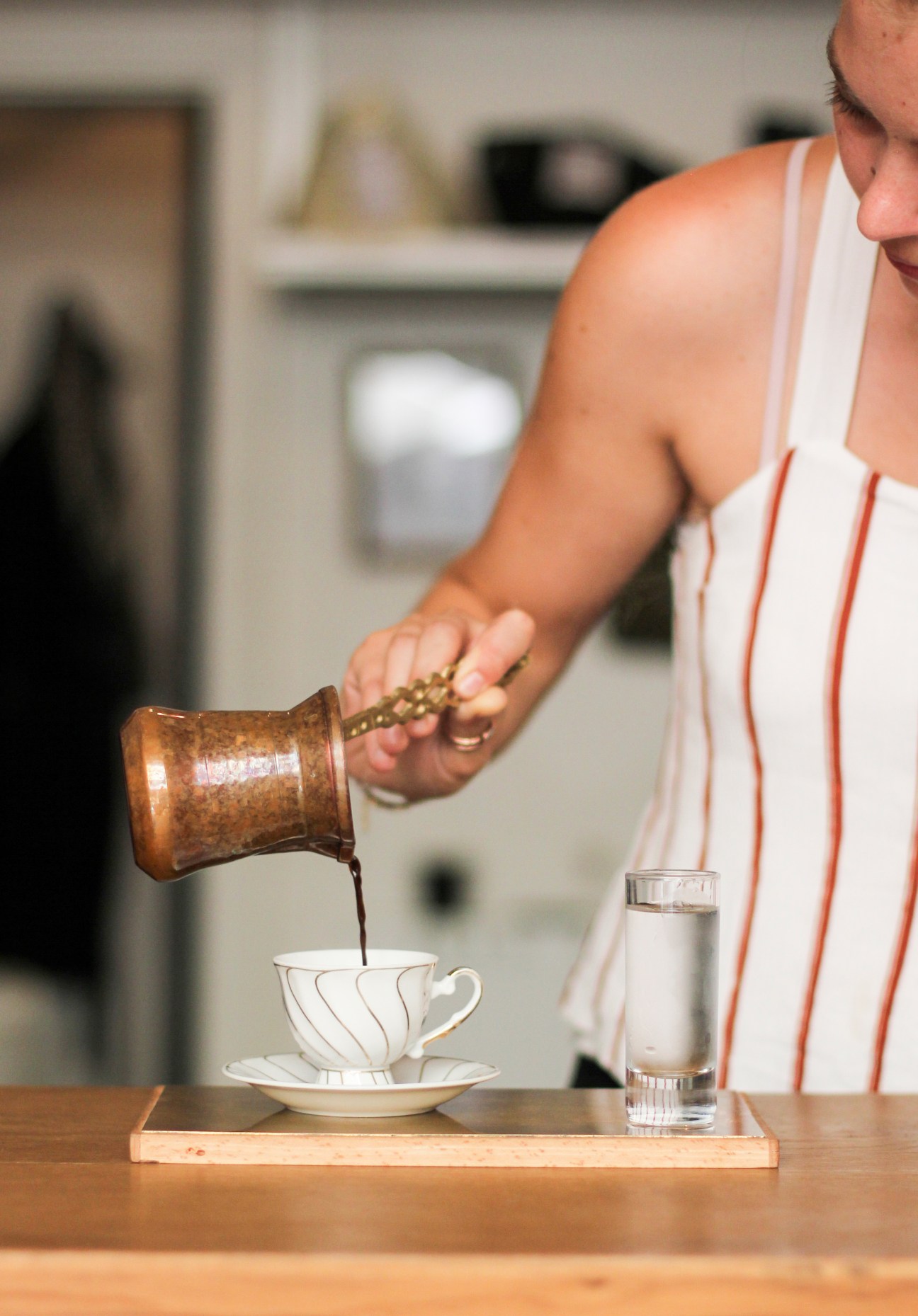 Person pouring coffee from a copper Turkish coffee pot into a white cup at Four Letter Word café in Istanbul.
