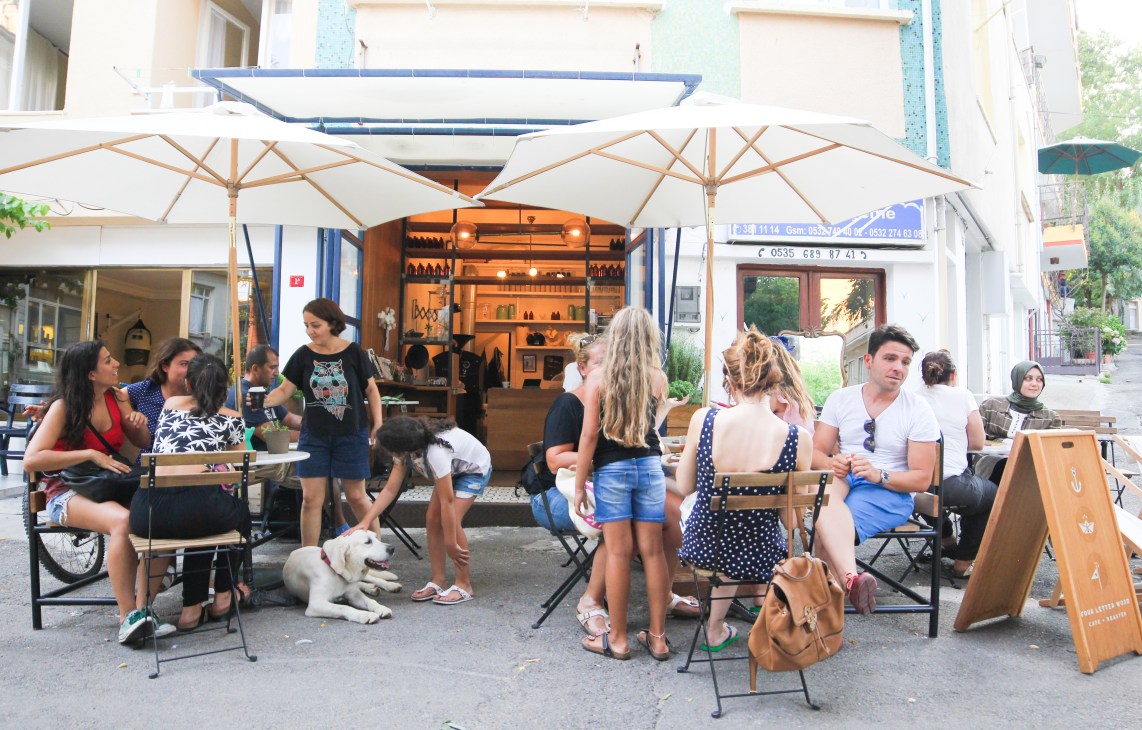 Four Letter Word café in Istanbul with customers seated under umbrellas outside the storefront.