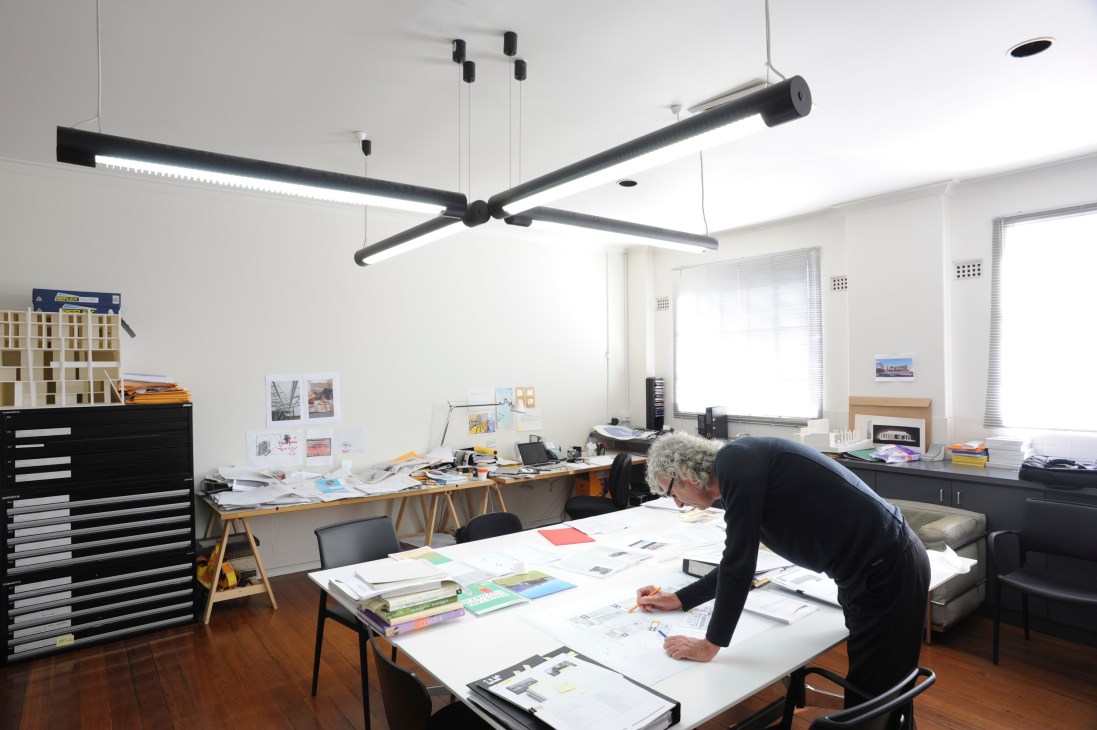 Interior of Donaldson + Warn architects' office with designer working at table under modern pendant lighting.