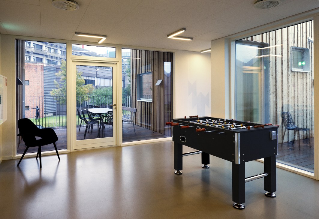 Table football game in a bright first-floor room with large windows overlooking an internal courtyard and seating area.