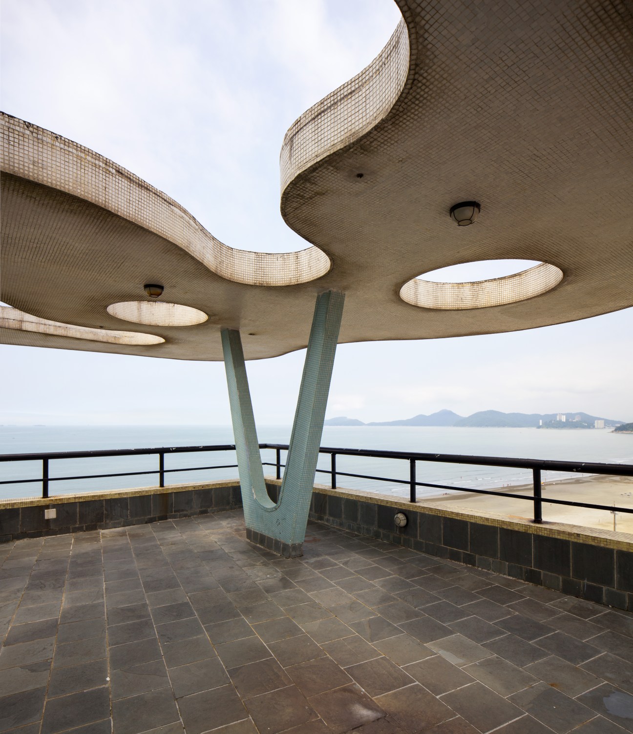The roof's concrete slab canopy with tiled columns overlooks Santos beach and bay.