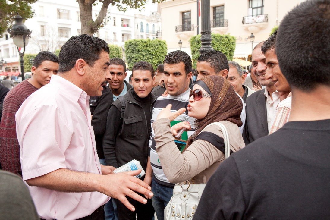Woman debating the headscarf issue with a group of men in a public square in Tunis.