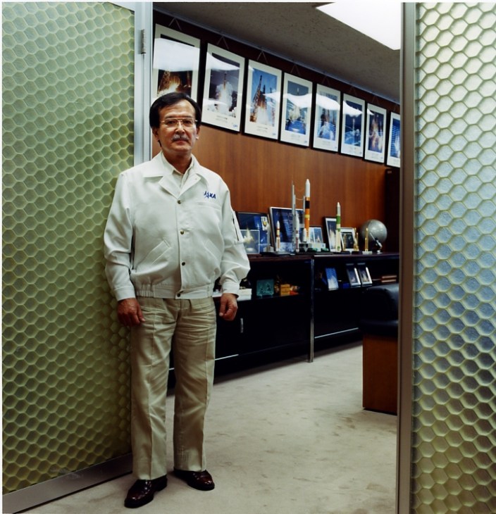 Norio Sakazume, JAXA space center director, standing in his wood-panelled office wearing a white JAXA jacket.