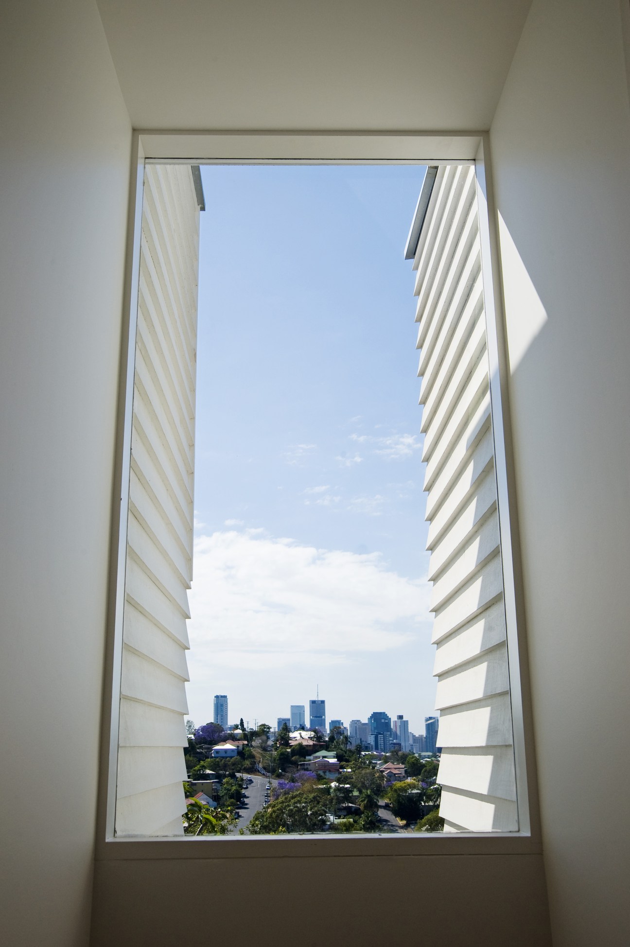 Brisbane city skyline viewed through large window with bespoke ventilation shutters.
