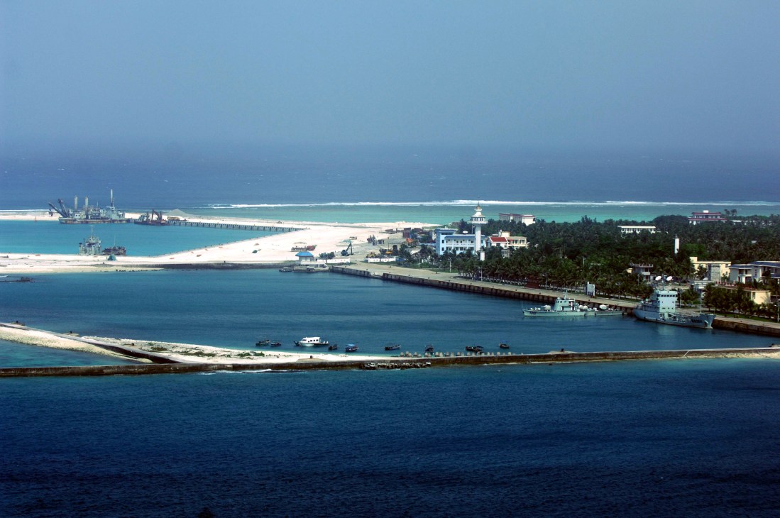 Aerial view of Sansha island in the South China Sea with turquoise waters, white-sand beaches, port facilities, and buildings.