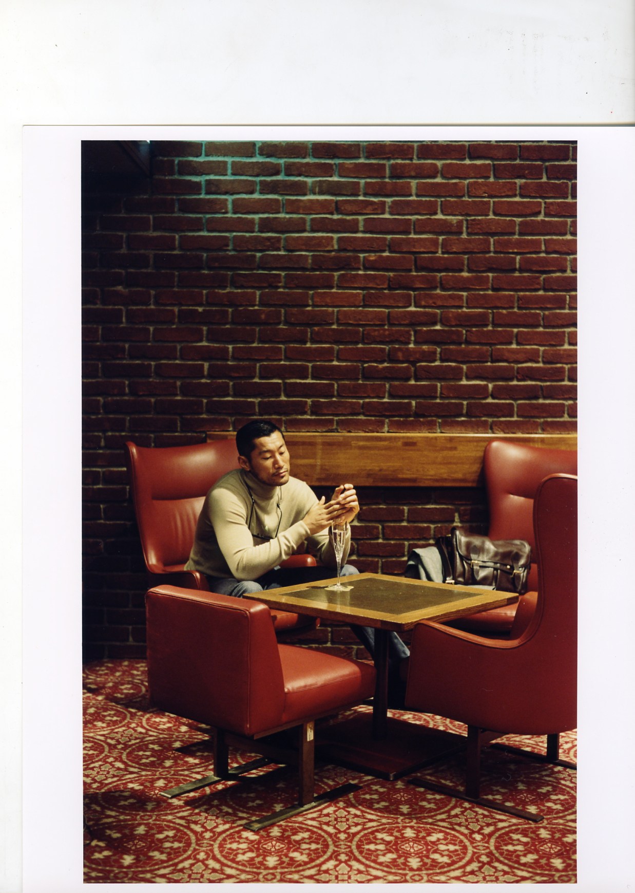 Man seated in red leather armchair at Brillant Bar, Keio Plaza Hotel Tokyo, wearing Hackett jacket and Bottega Veneta jumper.