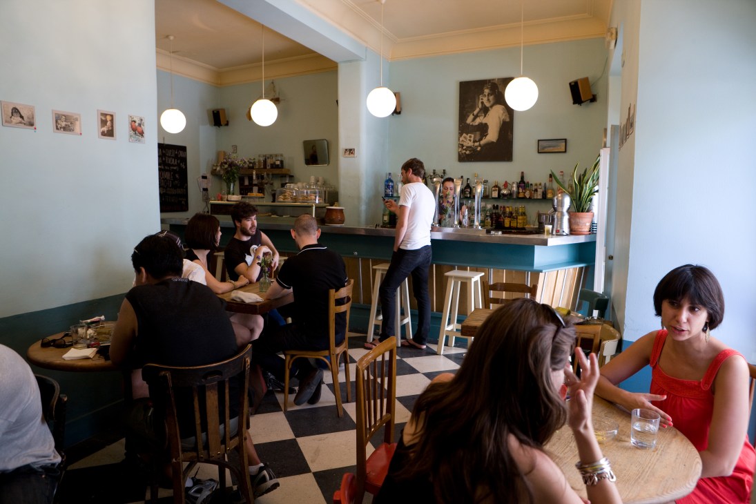 Interior of Bar El Rincón with customers seated at tables and staff at the counter under pendant lights.