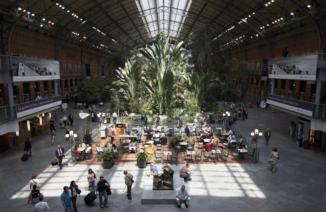 Overhead view of Atocha Station in Madrid with tropical plants, dining areas, and travelers