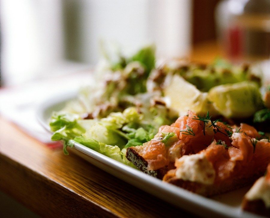 A plate of food with greens and sliced meat garnished with rosemary at Simple café.