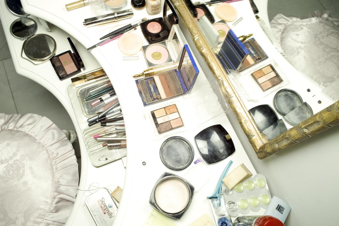 Lili Ivanova's dressing table with cosmetics, makeup brushes, eyeshadow palettes, and beauty products arranged on white surface.