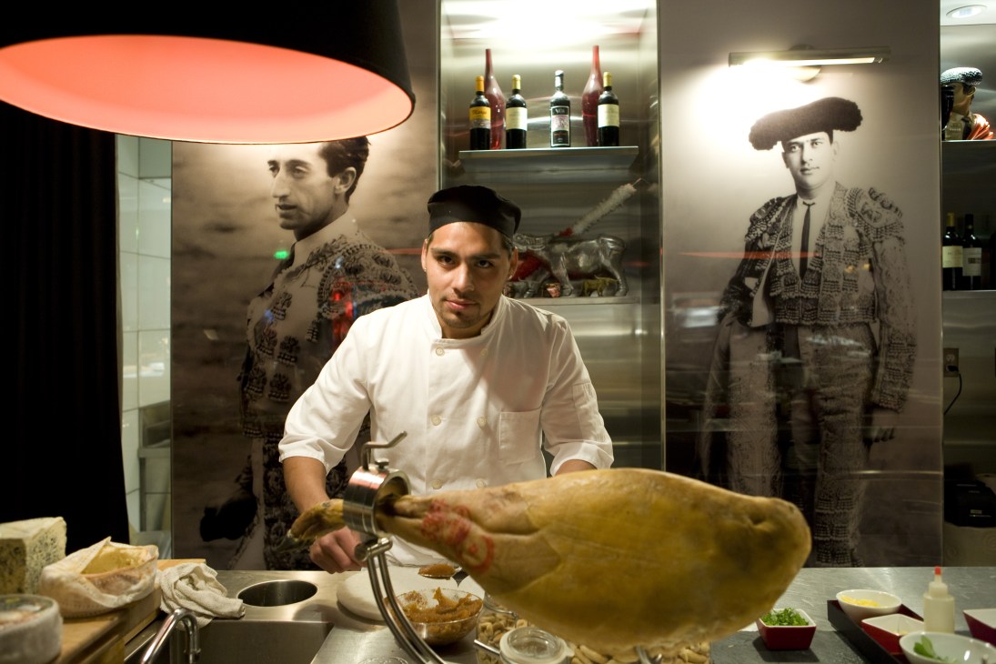 A sous chef in white chef's coat carves meat at the counter in The Bazaar's Rojo y Blanca dining room.