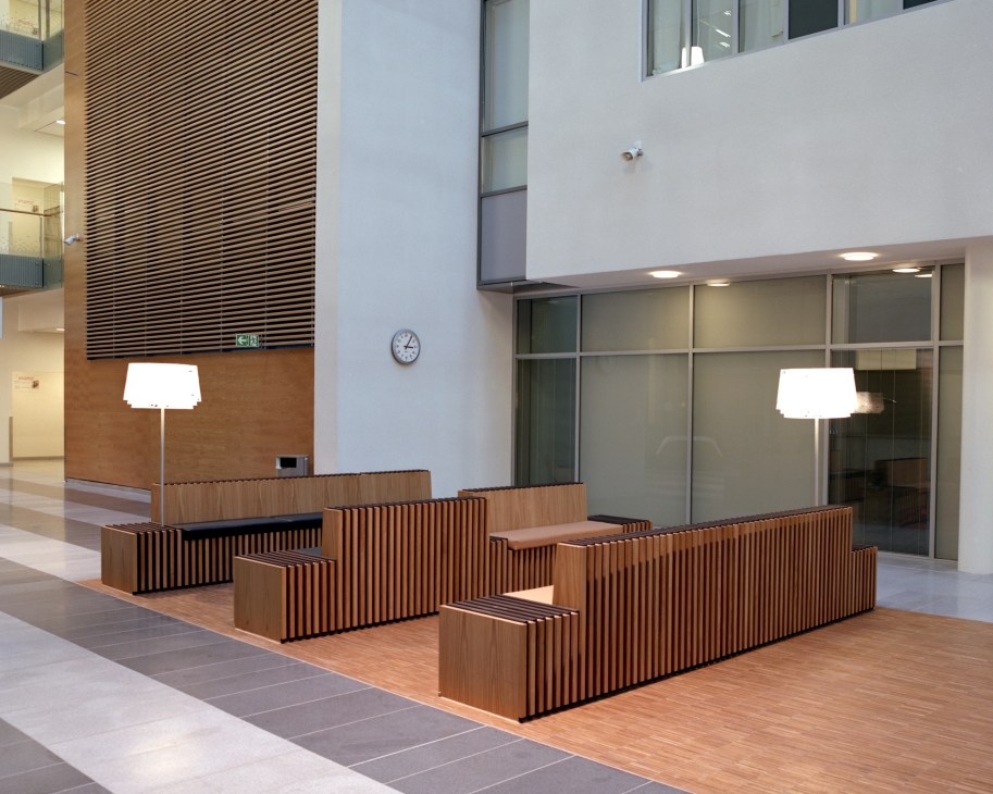 Hospital interior with custom wood-slat seating and Louis Poulsen pendant lights by Louise Campbell
