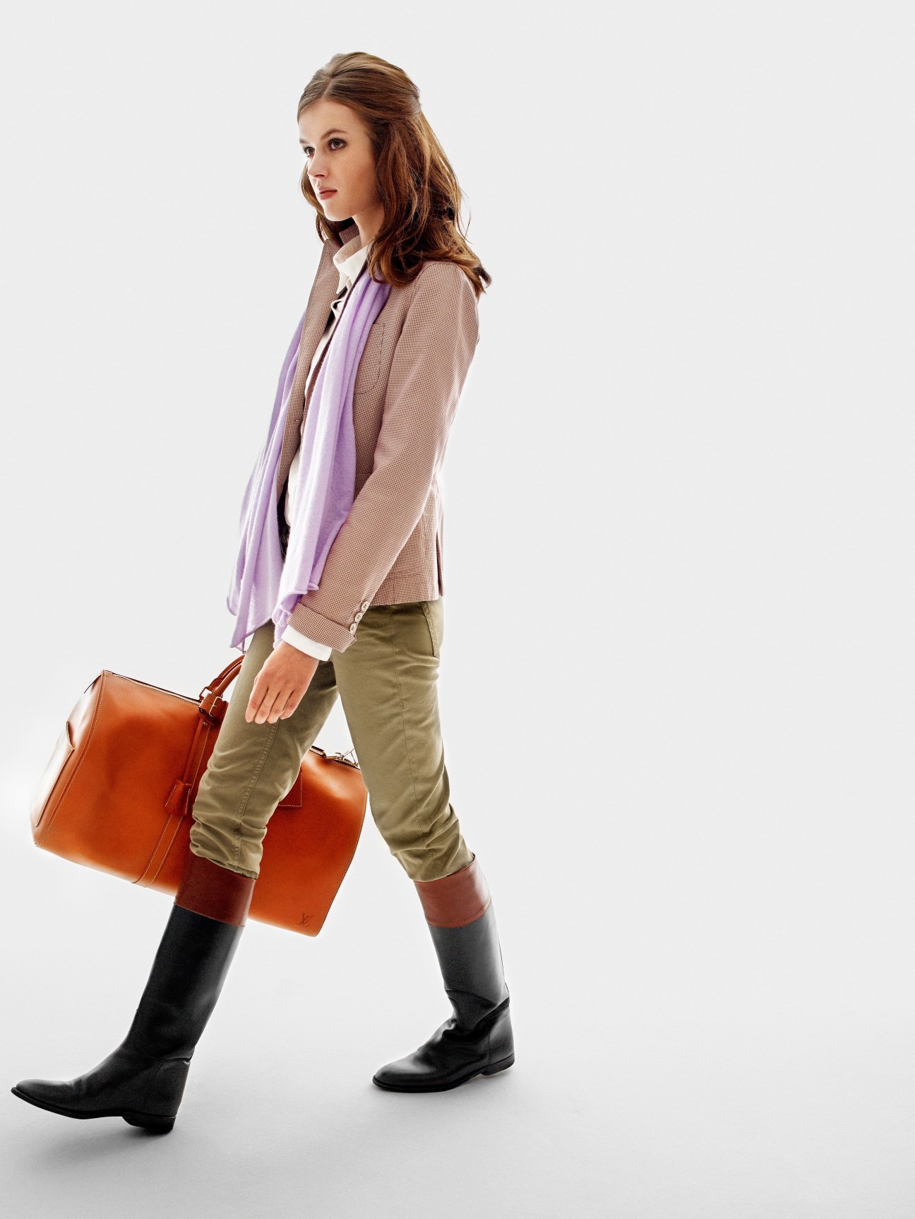 Model wearing a beige Montedoro jacket, purple N100 scarf, olive Fay trousers, black Hermès boots and cognac Louis Vuitton bag.