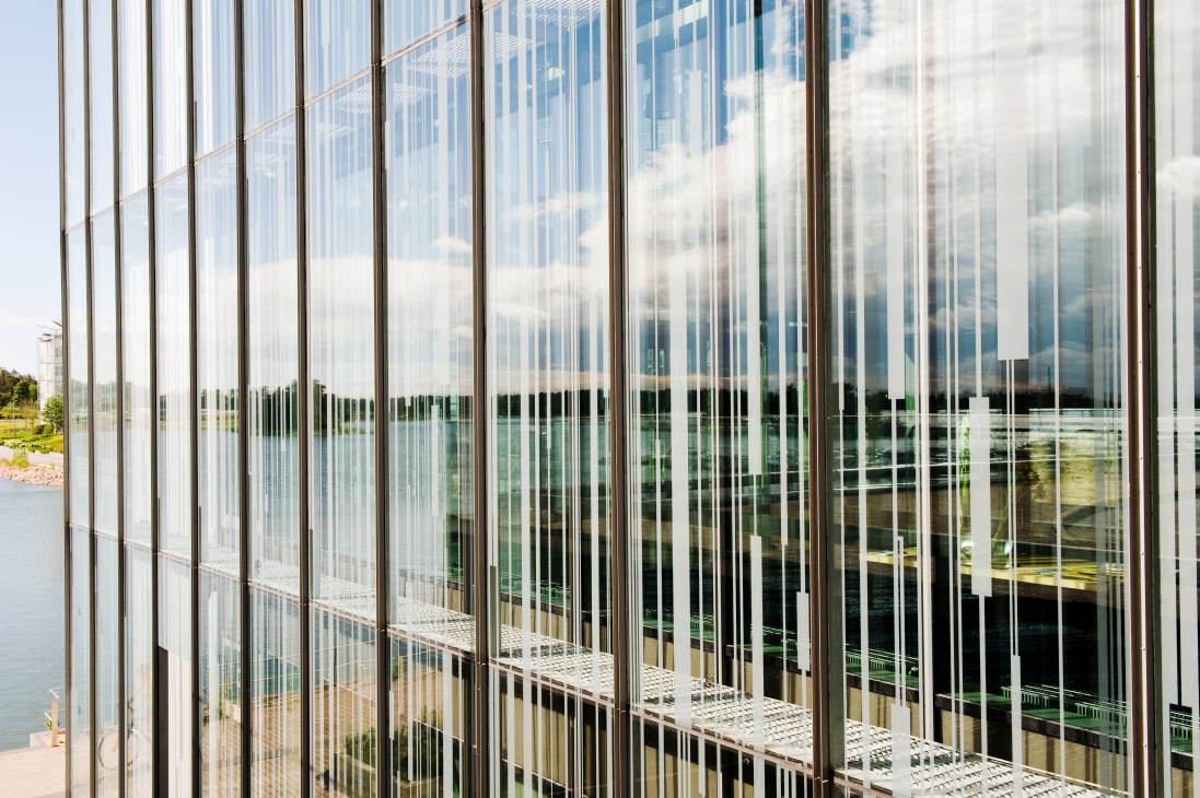 Glass facade of Kone building in Espoo, Finland overlooking landscaped grounds and water.