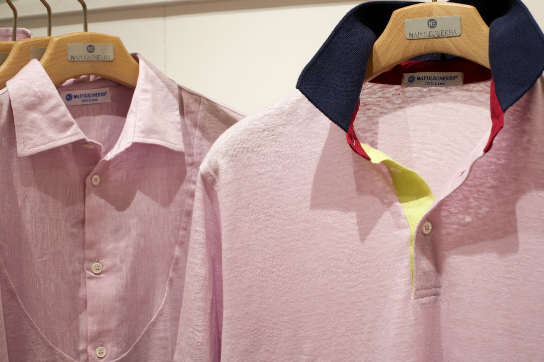 Polo shirts and button-up shirts by Napoleonerba on wooden hangers, displaying pink and navy colorways with contrasting collars.