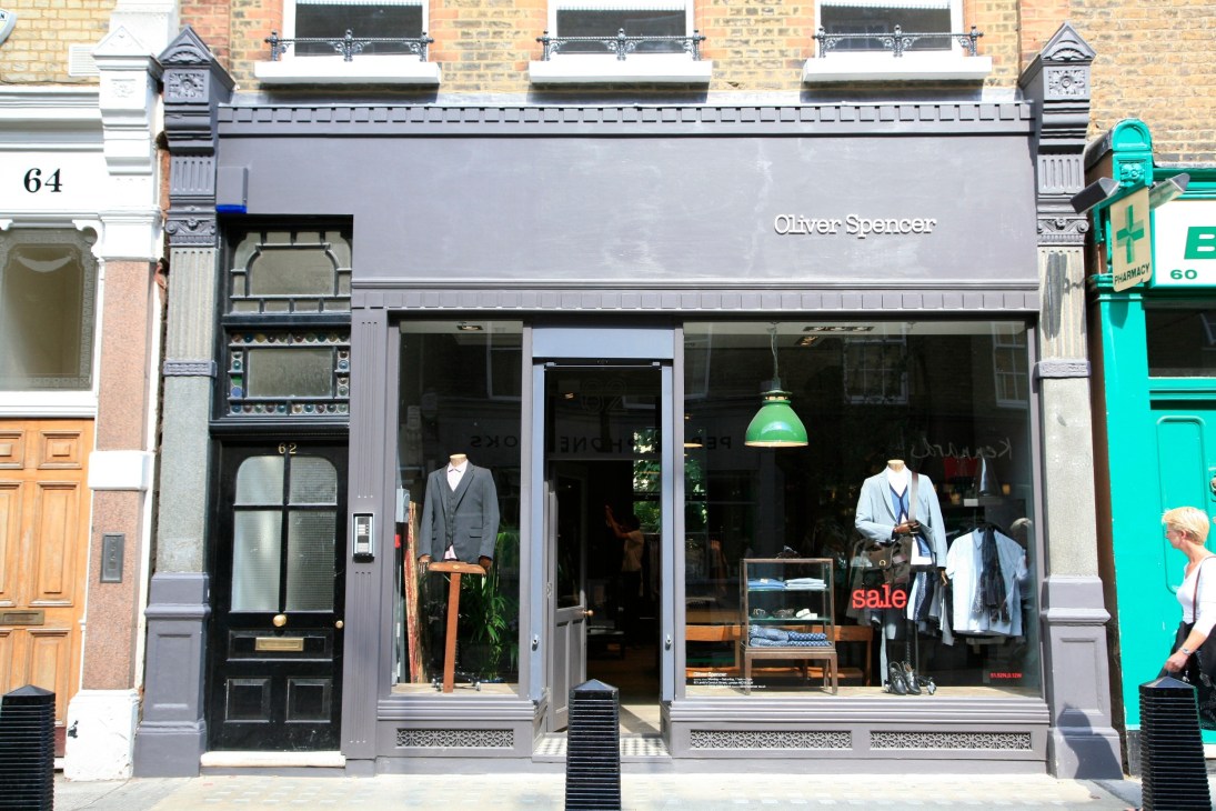 Oliver Spencer storefront with grey facade, mannequins in windows, and Victorian architecture on Lamb's Conduit Street.