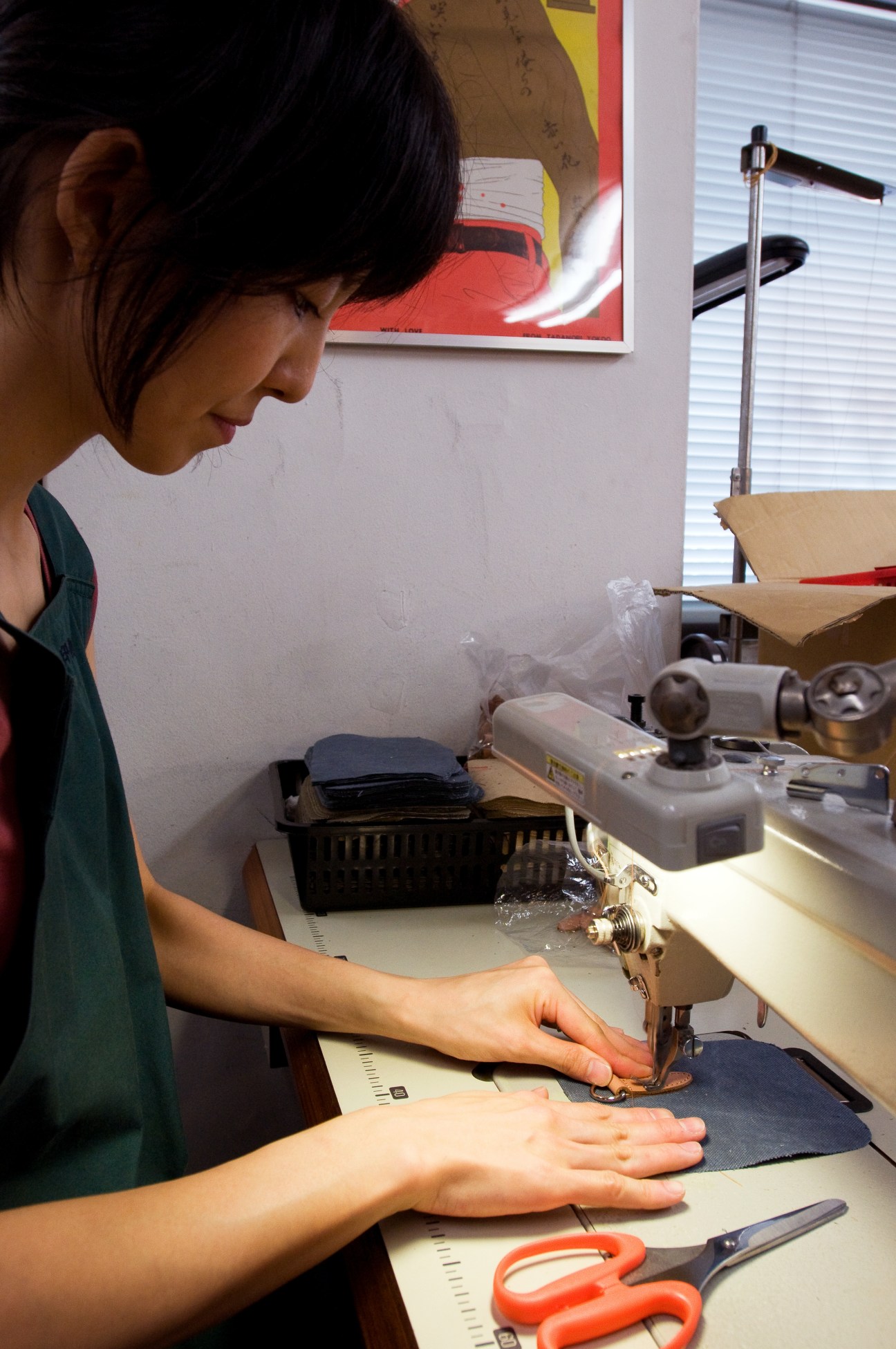A machinist stitches personalization onto dark fabric at a sewing machine in the Inujirushi workshop.