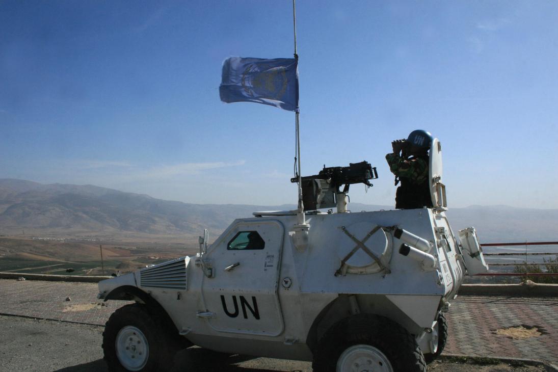 UN peacekeeper in armored vehicle with flag monitors Israel border in southern Lebanon.