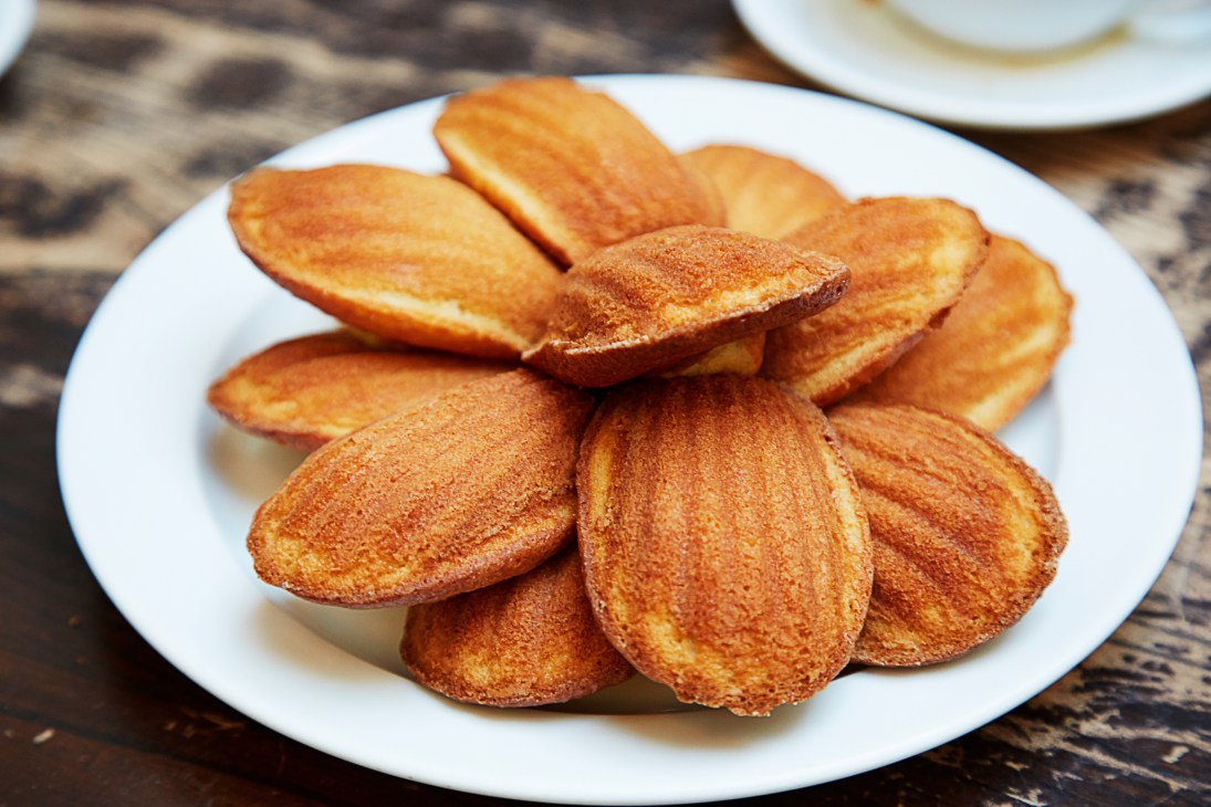 Golden-brown madeleines dusted with sugar on a white plate at St John restaurant.