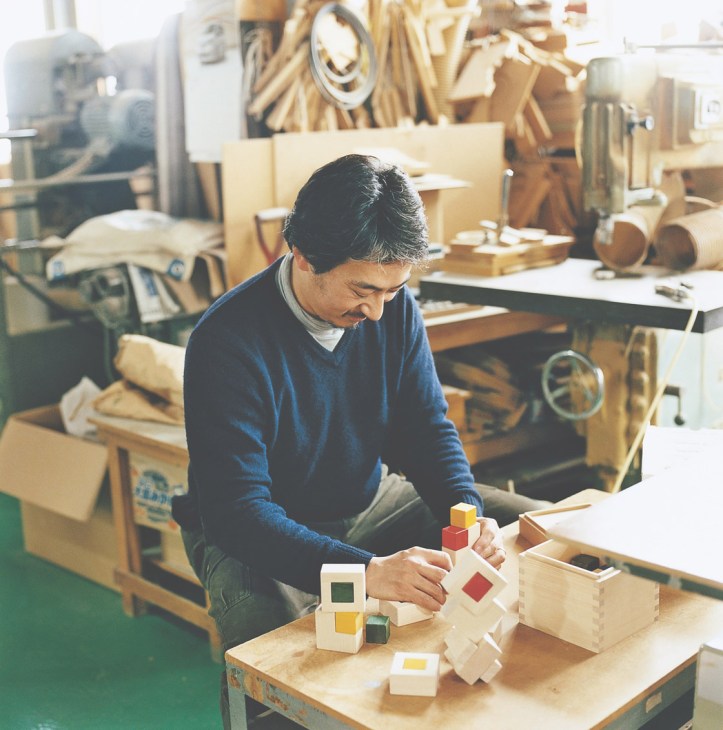 Shuhei Tominaga, chief designer, assembles wooden toy blocks in the workshop.